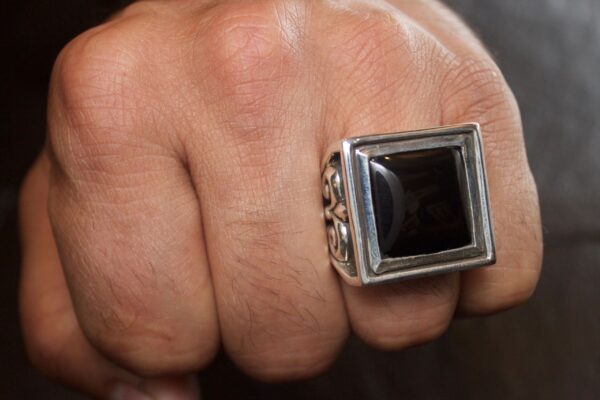 Close-up of a hand wearing a large square black stone ring.