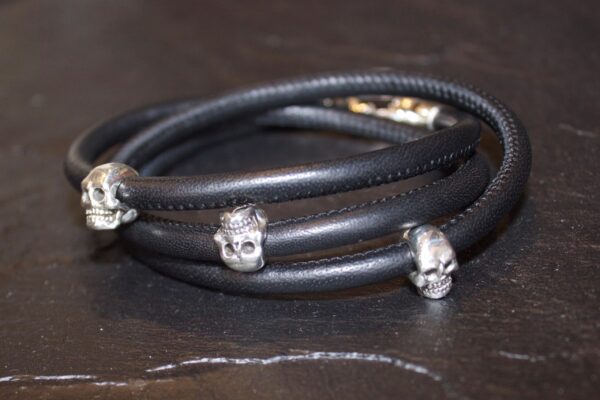 Black leather bracelet with silver skull beads wrapped in a spiral.