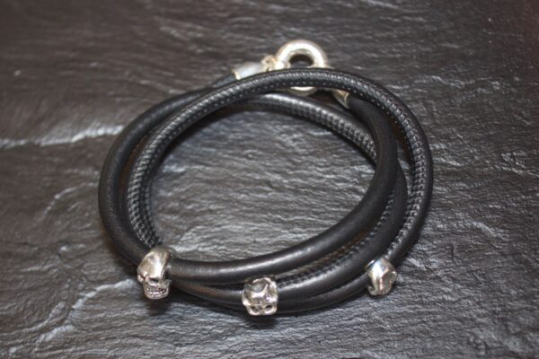 Black leather wrap bracelet with silver skull accents.