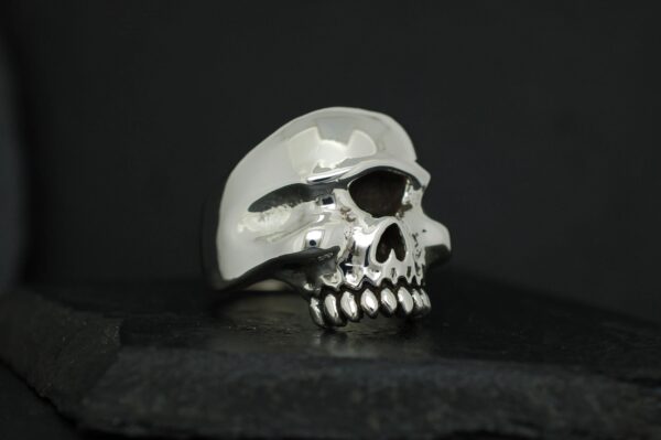 A shiny silver skull sculpture on a dark background.