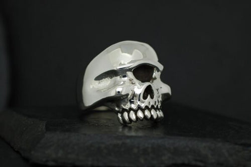 A shiny silver skull sculpture on a dark background.