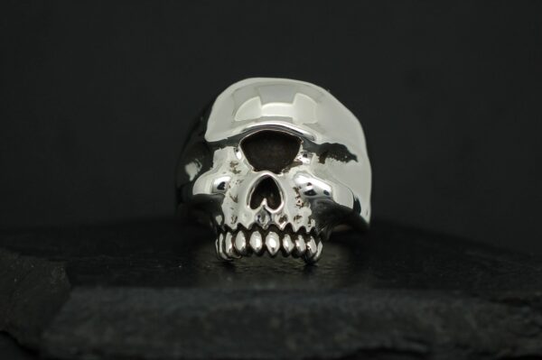 A shiny metallic skull sculpture on a dark background.