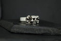Silver ring with a skull design on a dark surface.