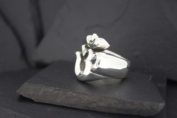 Close-up of a silver ring with a distinctive design on a dark surface.