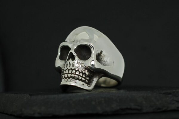 A silver skull-shaped ring with detailed teeth and eye sockets.