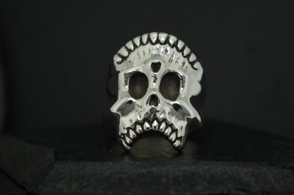 Silver skull-shaped ring with detailed teeth and hollow eyes.