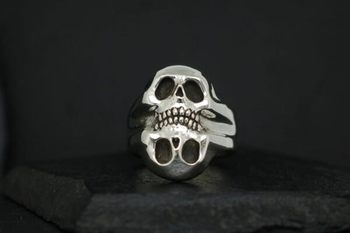 Silver skull ring with a split design against a black background.