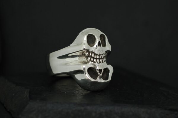 Silver skull ring with a heart-shaped detail on a black background.