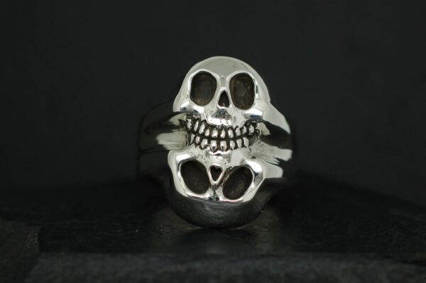 A silver ring featuring a detailed skull design with hollow eyes and teeth.
