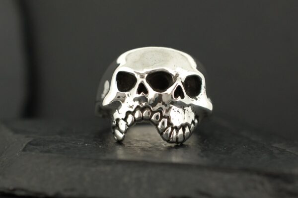 A silver ring designed as a detailed skull with hollow eyes and teeth.