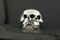A silver ring designed as a detailed skull with hollow eyes and teeth.