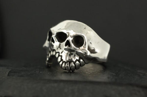A silver ring designed as a skull with detailed teeth and eye sockets.