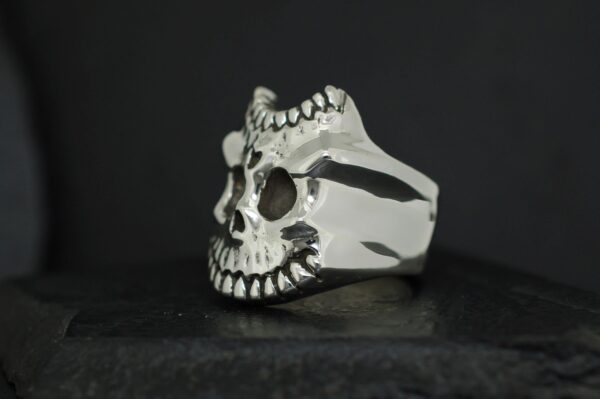 A silver ring shaped like a skull with intricate details.