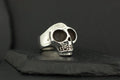A silver skull-shaped ring on a dark surface.