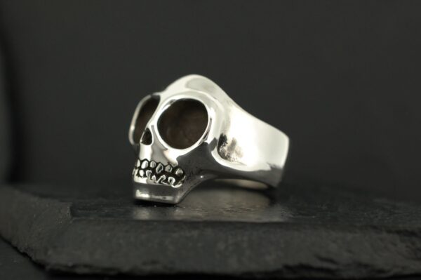 A silver skull-shaped ring on a dark surface.