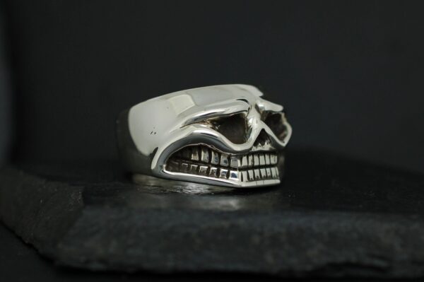 Silver skull-shaped ring with detailed teeth and goggles design.