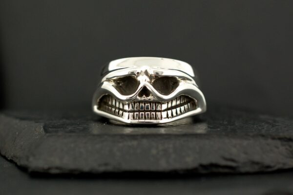 Silver skull ring with detailed teeth and hollow eyes.