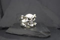 A silver skull ring with crossbones detail on a dark surface.