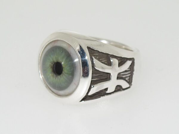 A silver ring featuring a realistic green eye and a cross design.
