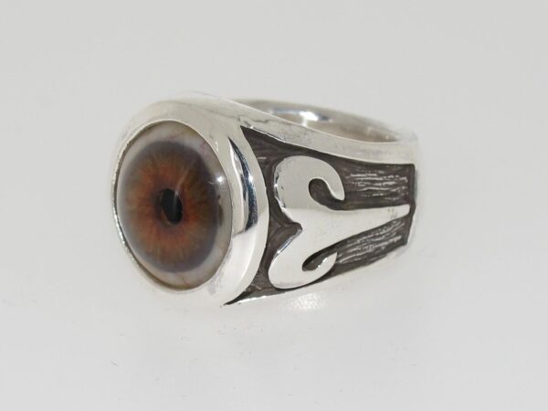 A silver ring featuring a realistic brown eye design.