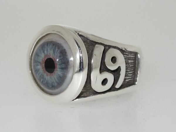 A silver ring with a realistic blue eye and zodiac symbols.