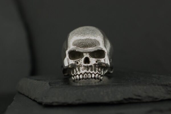 A metallic skull sculpture with detailed teeth and hollow eyes.