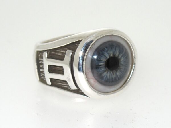 A silver ring with a detailed blue eye design on the top.
