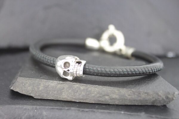 Close-up of a skull bead on a black leather bracelet.