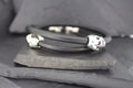 Black bracelet with silver skull accents on a dark background.