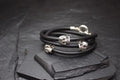 Black leather bracelets with silver skull beads on a dark slate surface.