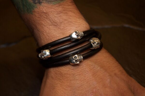 Black leather bracelet with silver skull accents on wrist.