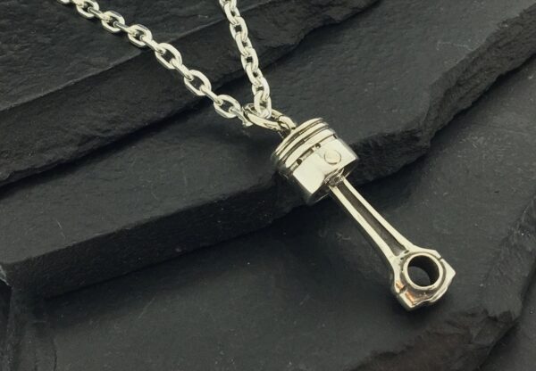A silver piston-shaped pendant on a chain necklace.