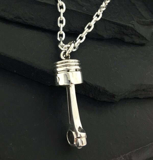 Silver piston pendant on a chain necklace.
