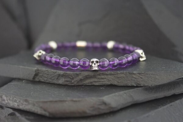 Elegant bracelet with purple beads and silver accents on a dark surface.