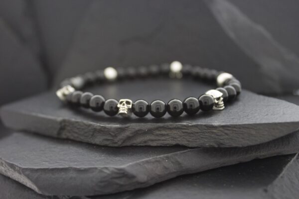 Elegant black bead bracelet with silver accents on dark stone.
