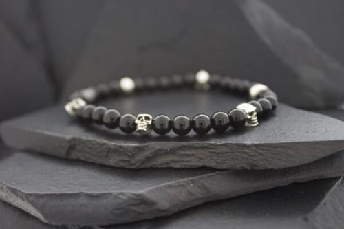 Elegant black bead bracelet with silver accents on dark stone.