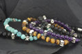 Beaded bracelets with skull charms in various colors on a dark surface.