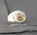A unique silver ring featuring a realistic amber-colored eye design.