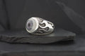 Silver ring with black flame design and round center stone.