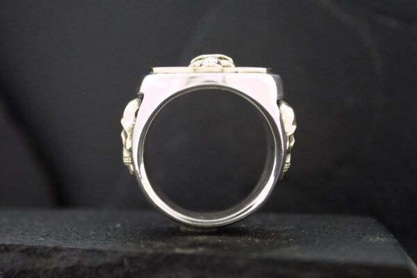Silver ring with a rectangular design and intricate side details.