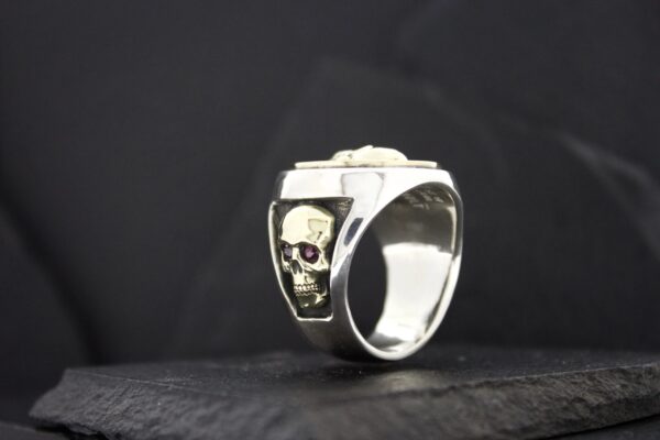 Silver ring featuring a skull design on a black background.