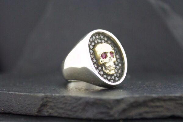 Silver ring with a skull design and red eyes.