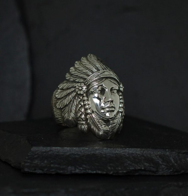 A silver ring featuring a Native American chief's face with a feathered headdress.