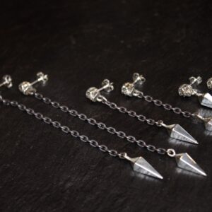 Silver chain earrings with geometric pendants on a dark surface.
