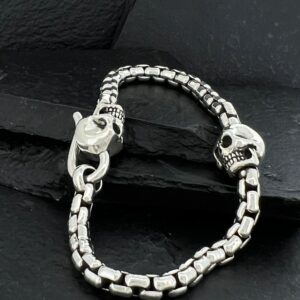Silver bracelet with skull and clasp details on a dark surface.