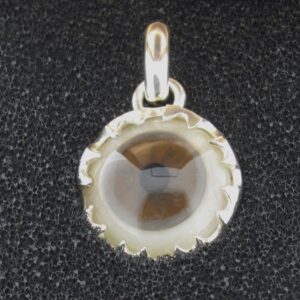 A round glass pendant with a silver frame on a black background.