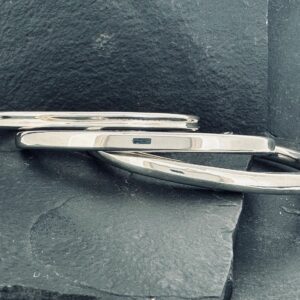 Two silver knives with black handles placed on a dark surface.