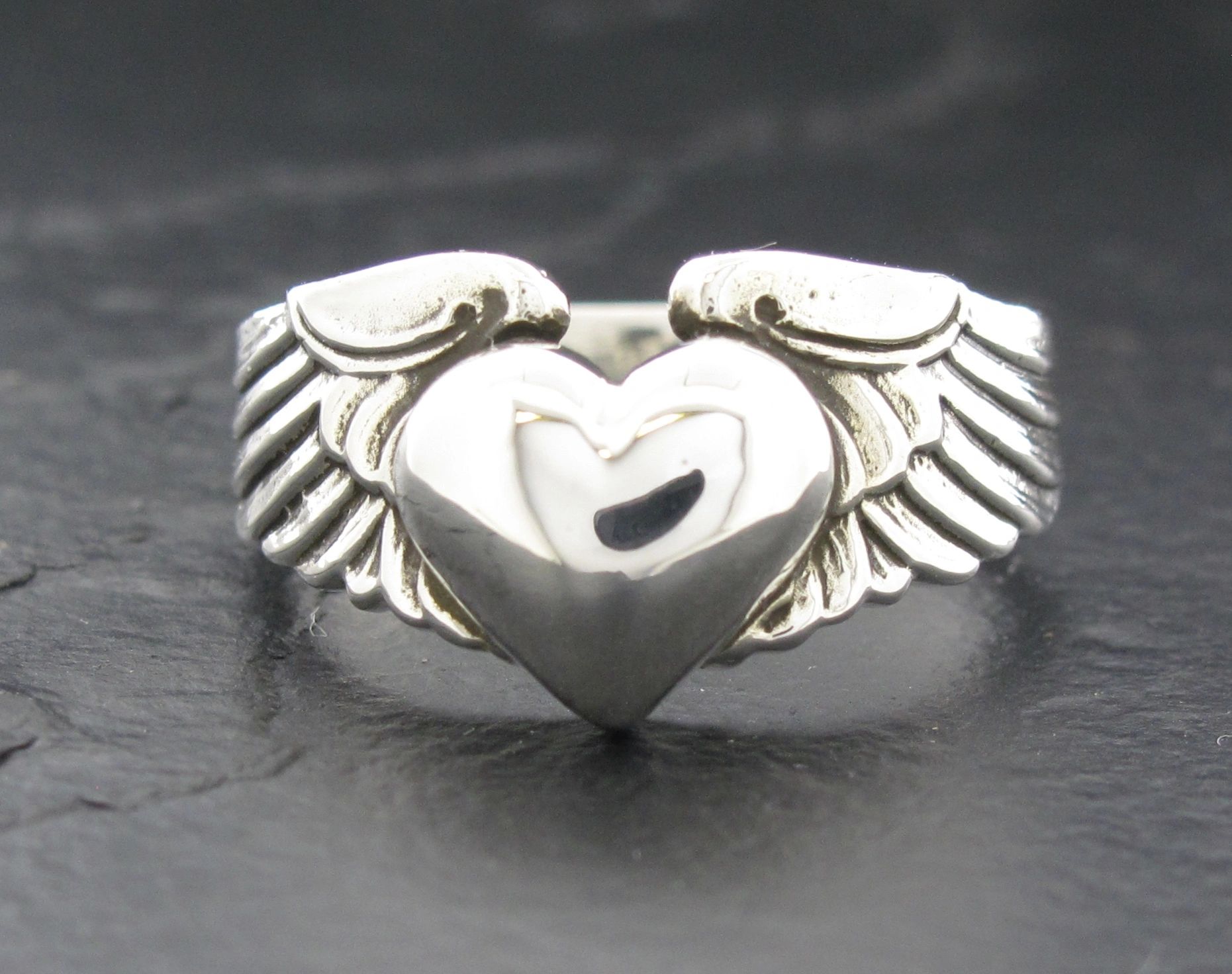 Silver ring with a heart and wings design.