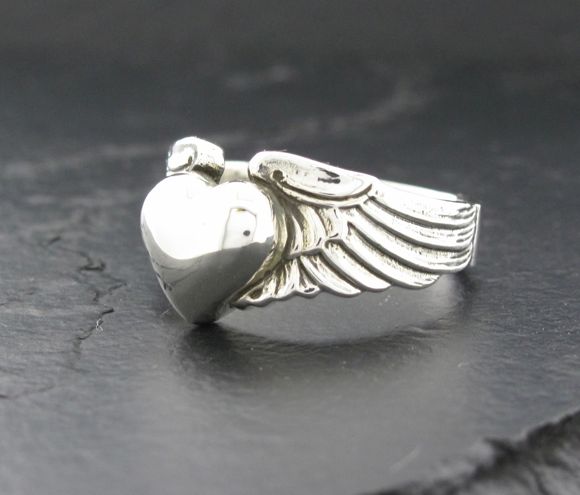 Silver ring with a heart and wings design.