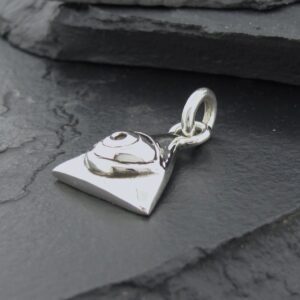 Silver heart-shaped charm with a small clasp on a dark stone surface.